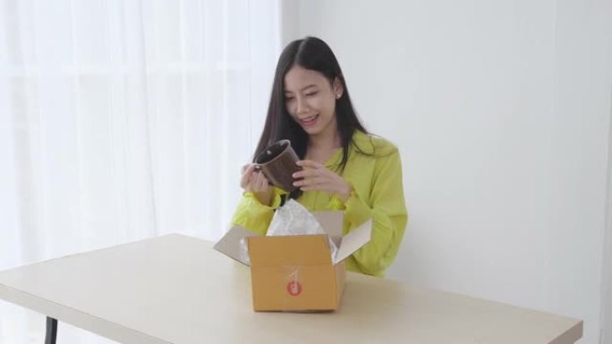 年轻的亚洲女性在家里满意的同时打开网上购物的包装箱，女性在网上商店购物时打开包裹，看起来很兴奋，送货