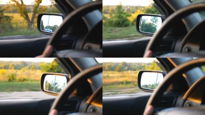 无法识别的驾驶员操纵车辆并穿越乡村高速公路。背景模糊农村环境的汽车后视镜视图。平静的夏季公路旅行。慢