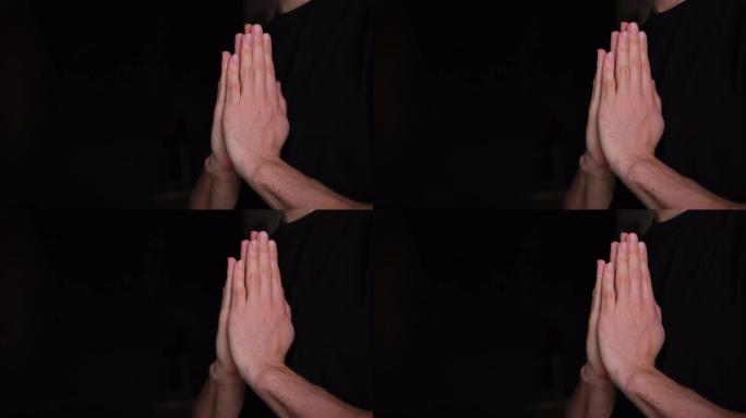 这家伙祈祷。一个人在黑色模糊的背景下双手合十祈祷，向上帝祈祷。他请求宽恕悔改的罪过。信徒家伙4k。