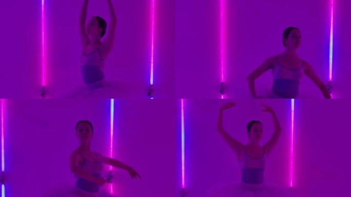 女人在霓虹灯的背景下在工作室里跳芭蕾舞并表演舞蹈元素。女孩以垂直的裂口抬起腿，然后进行转弯。慢动作。