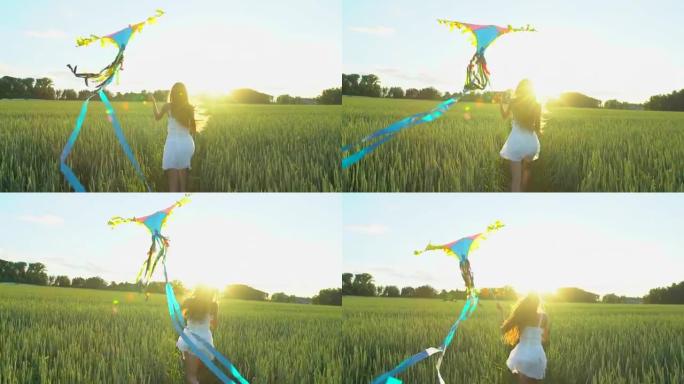 美丽的女孩，风筝在风中飞行在日落的麦田上奔跑