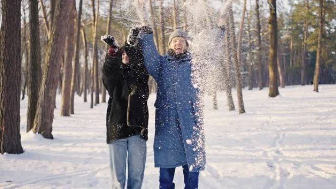 幸福的家庭在冬天的森林里玩得开心。一男一女正在扔雪。美妙的冬天阳光明媚的天气