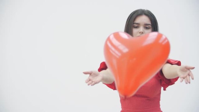 分手概念。沮丧女孩的慢动作视频拿着一个红心气球，同时思考单恋或分手，然后放下气球。