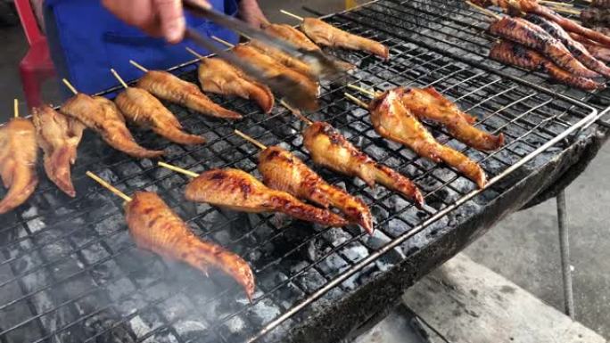 用竹子塞住的草药烧烤鸡翅，炉子上的鸡肉烤架，泰国的街头食品。