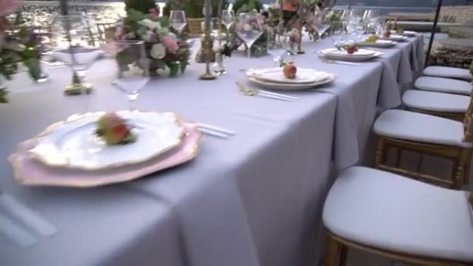 婚宴上的一张桌子，上面装饰着鲜花，烛台上燃烧的蜡烛和海边码头上的年轻石榴