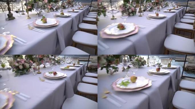 婚宴上的一张桌子，上面装饰着鲜花，烛台上燃烧的蜡烛和海边码头上的年轻石榴