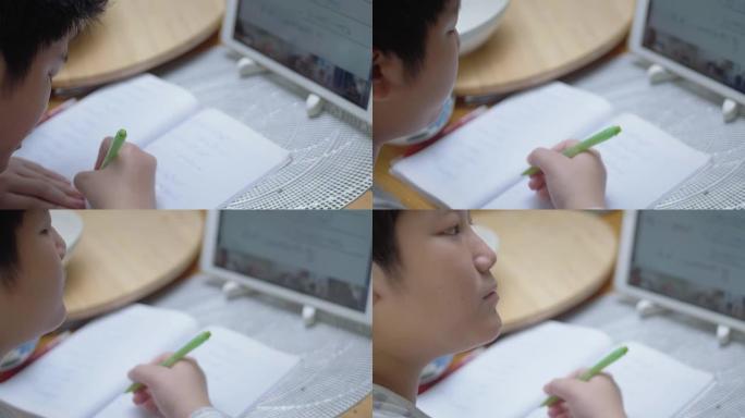 亚洲男孩使用数字平板电脑与老师和朋友在家里的餐桌上在线学习，这是新的正常生活方式概念。