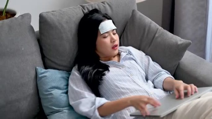 年轻的亚洲女商人感到头痛和发热。她睡在客厅的沙发上。在家工作，女商人和工作观念。