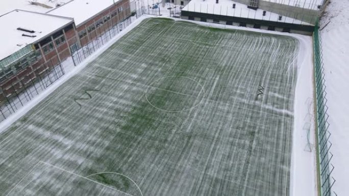 从雪地上清理足球场。落在足球场上的雪。清理足球场上积雪的机器。为冬季比赛准备足球场