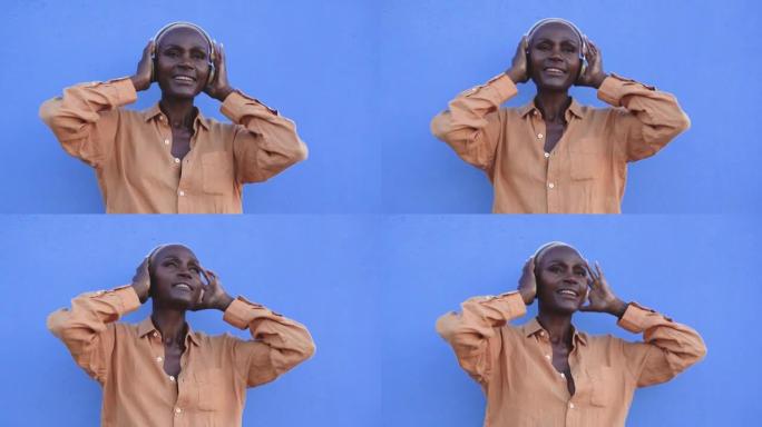开朗的非洲高级妇女戴着耳机，在城市户外跳舞播放列表音乐