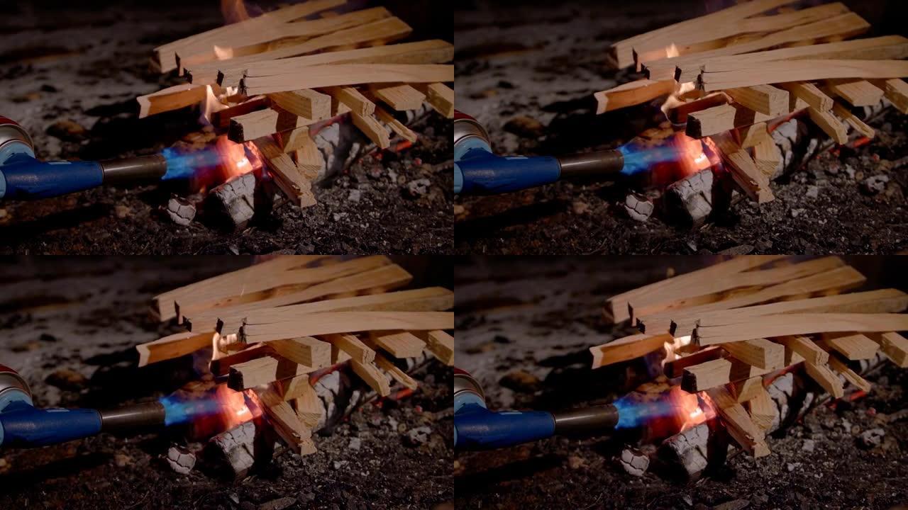 特写慢动作拍摄木火开始升起，一名男子用煤气炉点燃火