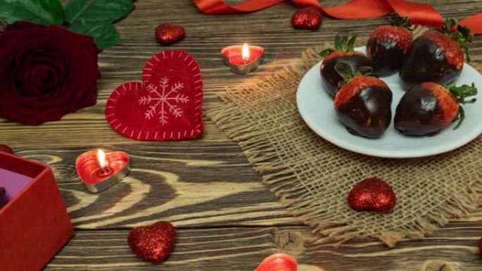 圣情人节。盒子上有巧克力覆盖的草莓，心形，蜡烛，红玫瑰。从上方观看。情人节。庆祝。4K