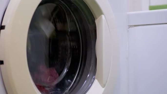 用家用洗衣机洗彩色衣服。旋转滚筒。缩放
