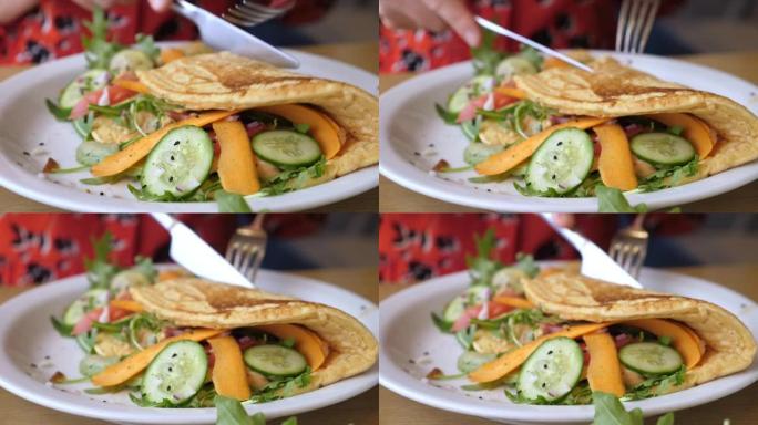 女性的手用蔬菜切煎蛋卷。健康的有机早餐配白盘。健康生活方式理念