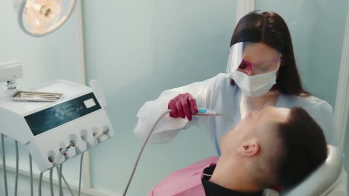女牙医在牙科诊所治疗病人。一个女人用气流缩小了嘴