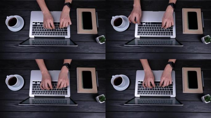 女孩的手的俯视图，他们正在打开的笔记本电脑上打字，写电子邮件，浏览互联网。笔记本电脑在一杯咖啡和一部