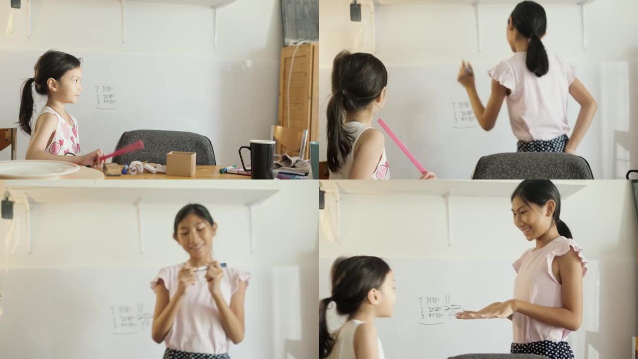 快乐的亚洲女孩用白板为姐姐教数学，女孩在家锻炼，新型冠状病毒肺炎在家上学。