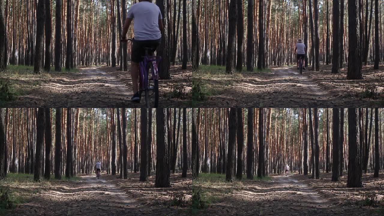 年轻人骑着自行车在穿过森林的路上。狭义聚焦。