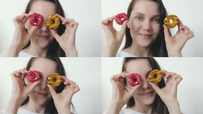 一个美丽的女人，有着蓝色的眼睛和愉快的微笑，给她的脸上带来了多色的甜甜圈，圆形的甜甜圈，装饰着黑巧克