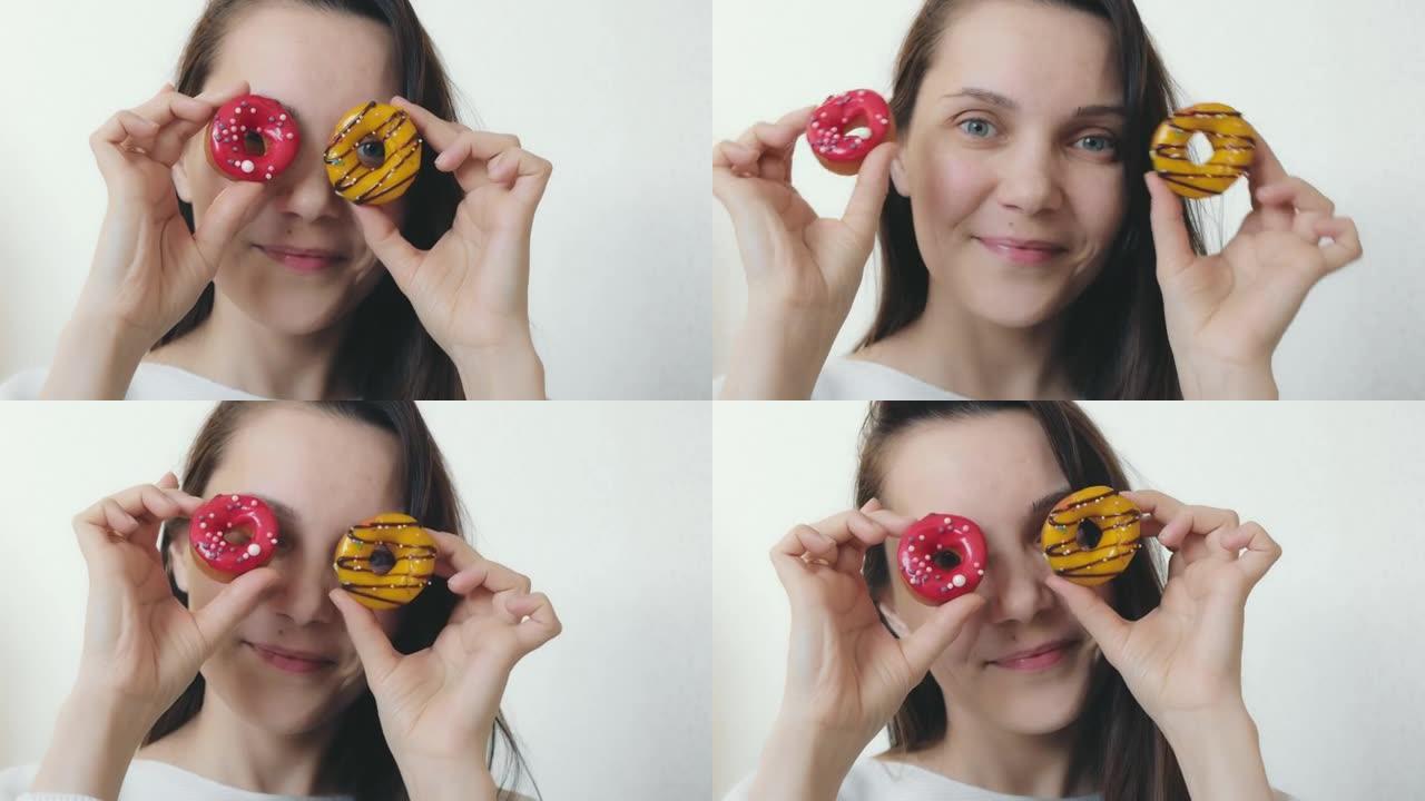 一个美丽的女人，有着蓝色的眼睛和愉快的微笑，给她的脸上带来了多色的甜甜圈，圆形的甜甜圈，装饰着黑巧克