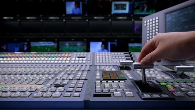视觉切换器工作室导演广播视频混合器操作-手的特写。在视觉混合器上工作的摄影师的手，切换电视面板。