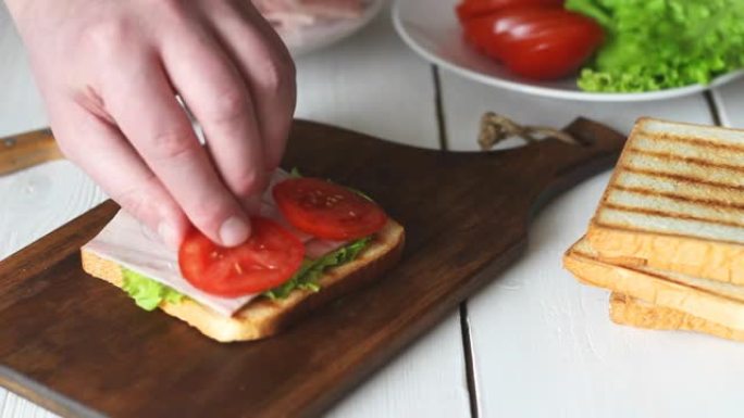 用沙拉，番茄，火腿和奶酪制作三明治的过程。美国美食。快餐。烹饪。
