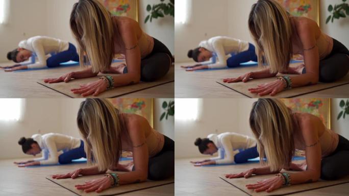 两个活跃灵活的女人练习鸽子瑜伽姿势
