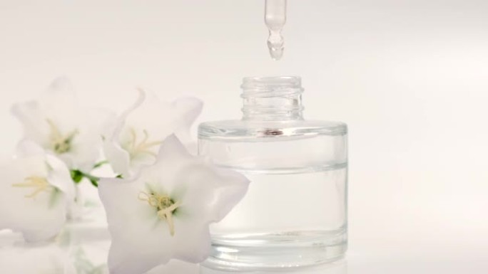 香水。精油产品。从化妆品移液器滴落到装有香水的玻璃瓶。皮肤和身体护理。芳香草本植物和花卉液体。美容和