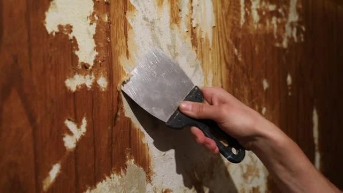 用刮刀修复公寓的墙壁，去除旧墙纸