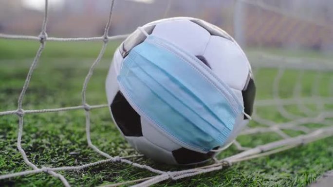 4k，体育场绿色草地上戴着医用面具的足球。球入网。