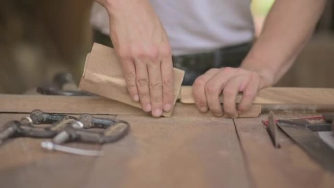 木匠在木工商店的木板上使用砂纸的特写镜头