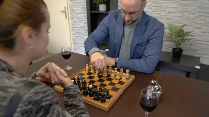 年轻夫妇坐在家里的桌子上下棋