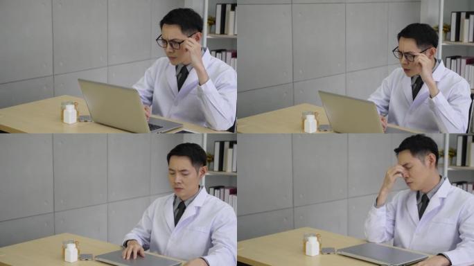 疲惫的亚洲男医生视力不好头痛或偏头痛关闭笔记本电脑
