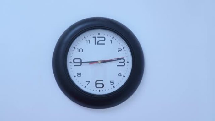 黑色圆形挂钟从白色墙壁背景开始。9:13时间。