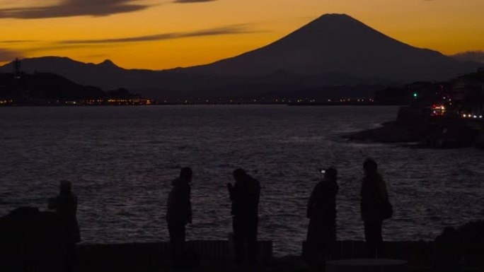 人们在拍照。从稻村加崎黄昏的富士山和江之岛