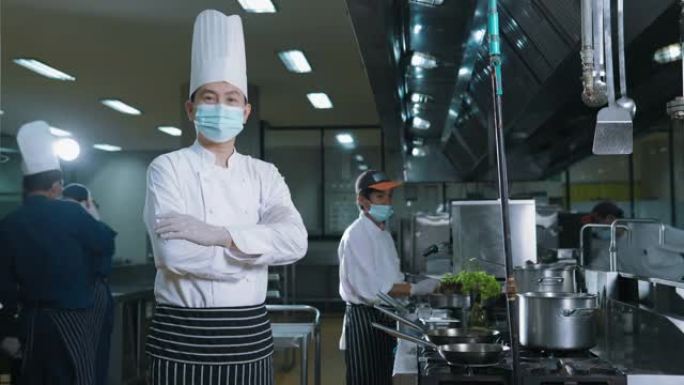 一位在餐厅厨房工作的亚洲男厨师的肖像，向相机展示了一盘食物