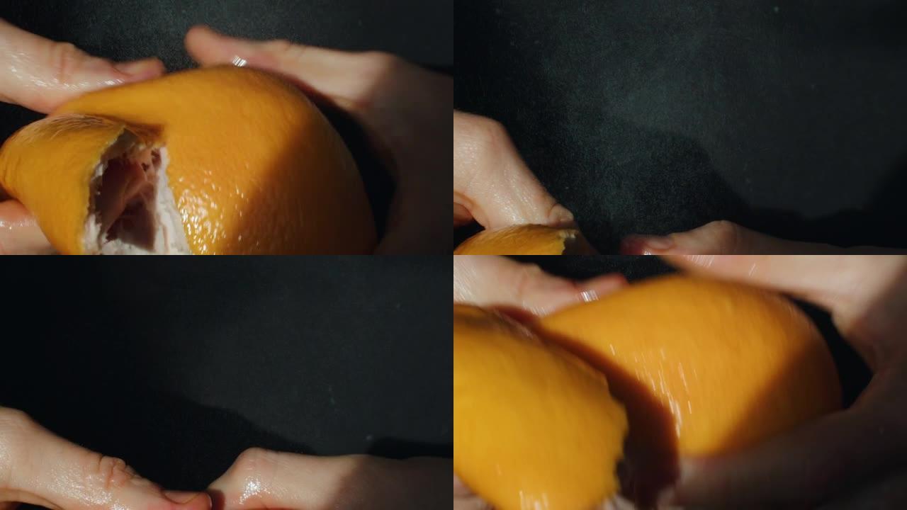 宏观男性手剥皮多汁葡萄柚在黑色背景慢动作。男子手持橙色水果喷洒在空气中的特写镜头。保健维生素抗氧化食