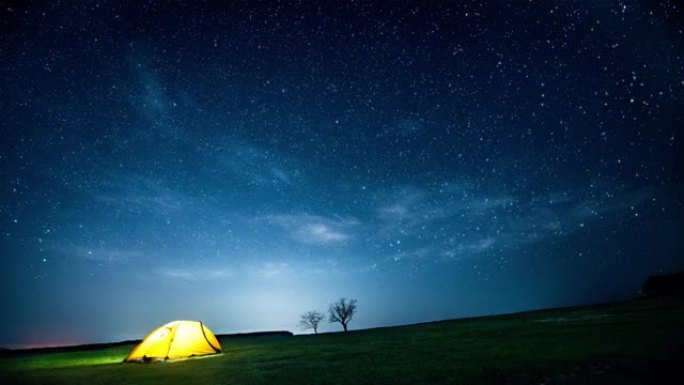 闪烁的星空下的夜山中发光的露营帐篷。电影。