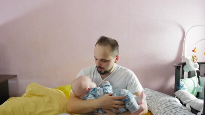 疲倦的父亲将哭泣的婴儿抱在怀里，试图躺下睡觉。幸福家庭理念。亲子关系概念。中枪。