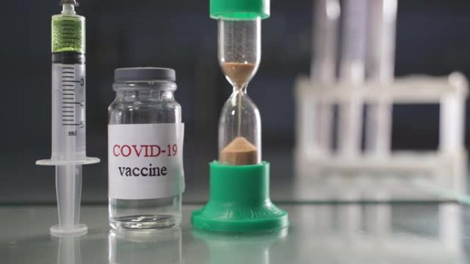 Covid-19疫苗注射器、空疫苗瓶和沙漏。注射器内装有抗covid-19药物液体。沙漏作为一个象征
