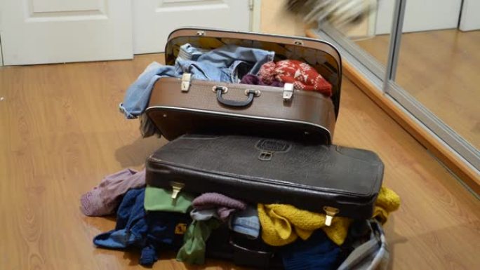 用过的衣服被扔到装满旧东西的手提箱上。整理衣柜和纺织品。可持续生活