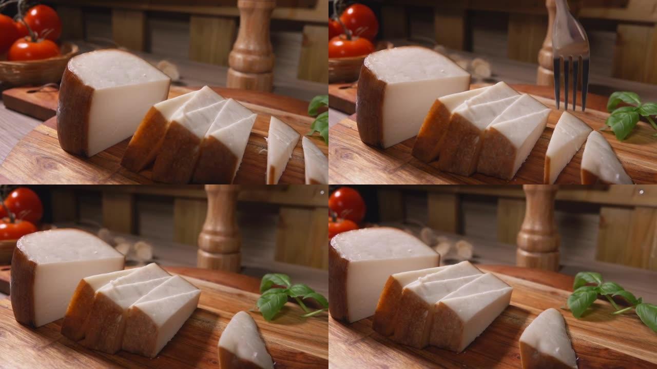 叉子的特写镜头从木板上拿了一块半硬奶酪