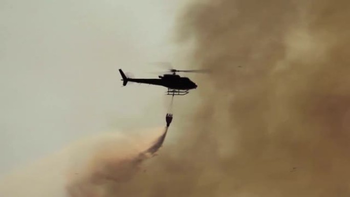 剪影消防直升机在森林大火中滴水