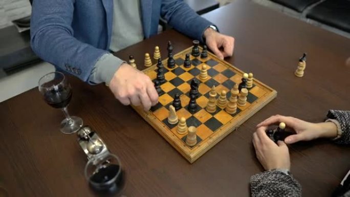 年轻夫妇坐在家里的桌子上下棋