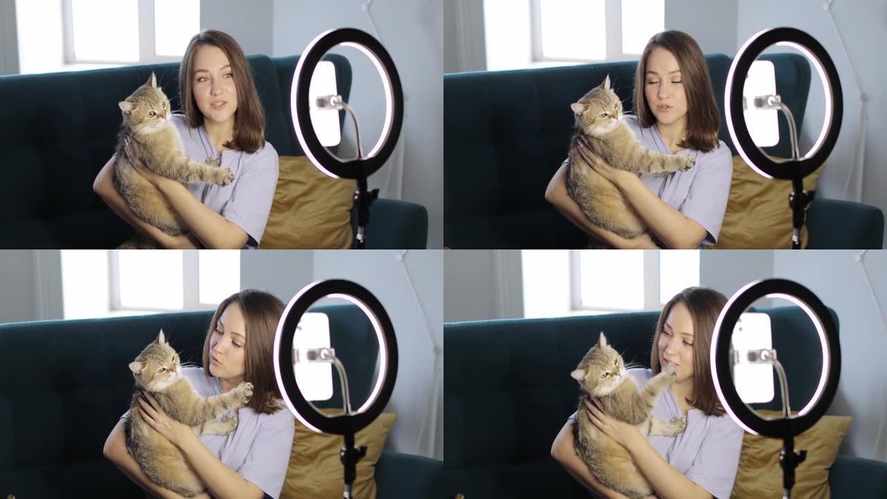 女人的博主和她的猫正在使用环形灯在智能手机上录制视频