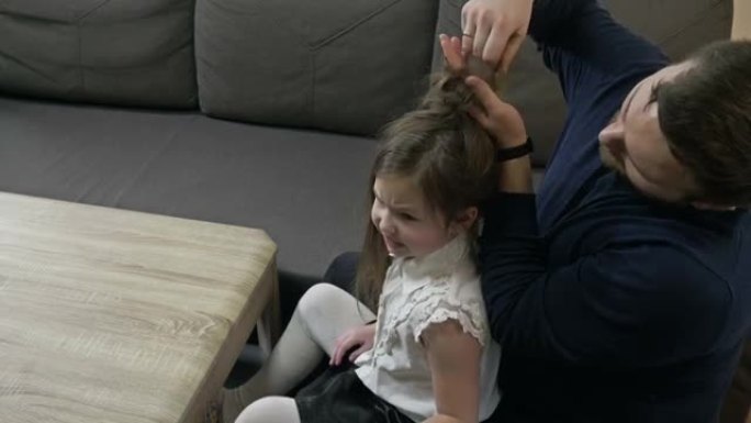 中年男子试图把他小女儿的辫子编成辫子。他不擅长这个。孩子生气了