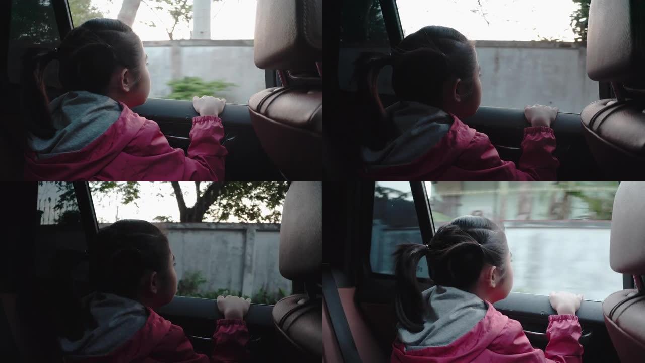 4k亚洲小女孩在车外看东西。早上，女孩在去学校的路上看着车窗外的东西。孩子们从车里看到街景放松。汽车