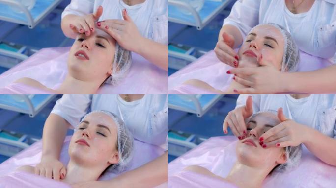 美容师在做面部按摩前，在女孩脸上涂上奶油，特写。