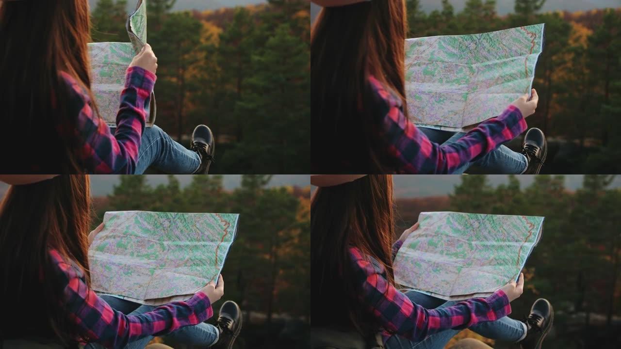 一位年轻女子坐在一块岩石上，手里拿着地图。她在规划一条路线。在山里徒步旅行。4K。