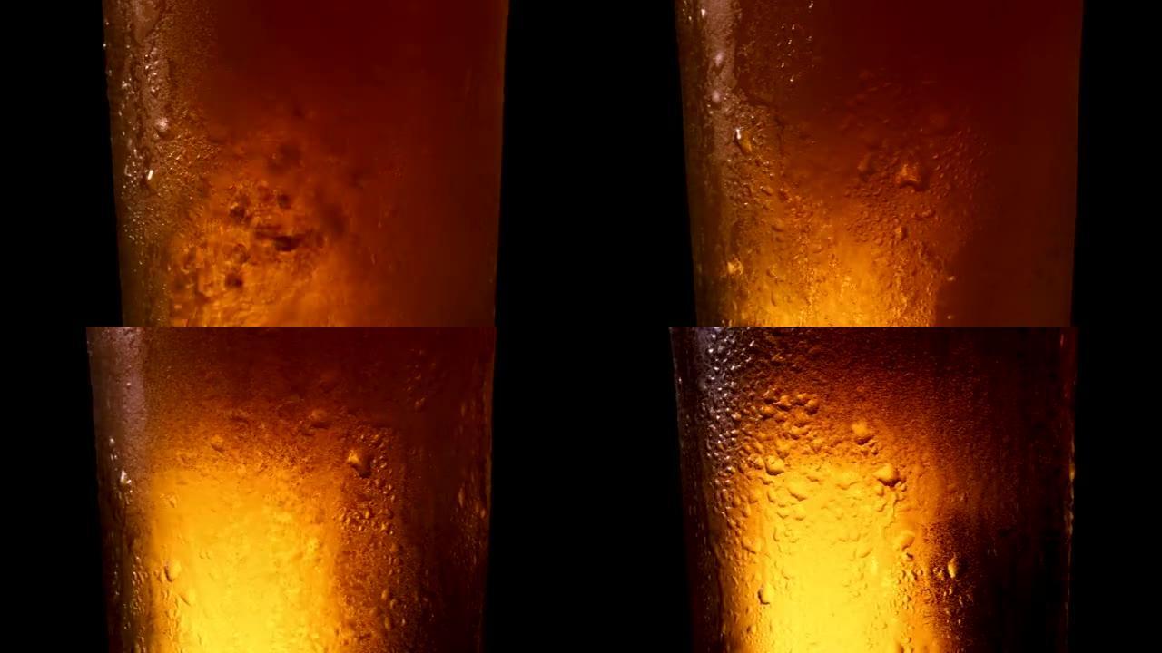 将冷啤酒倒入装有冷凝水滴的玻璃杯中。在黑暗背景上旋转